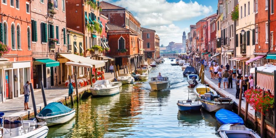 Canal, barcos e casas coloridas em Murano, ilha pertinho de Veneza, um dos lugares paradisíacos na Itália