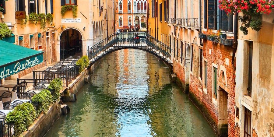 Canal romântico em Veneza, com casas coloridas e sacadas com flores