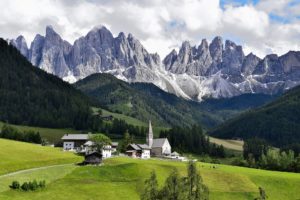 Vista da cadeia de montanha das Dolomitas, na itália, com cidade e campos verdes em primeiro plano