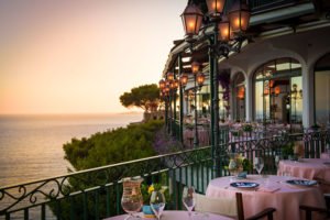 mesas, decoração e vista do mar no restaurante zass em posutano, um do slocais onde comer na costa amalfitana