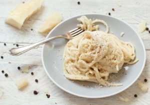 Prato de massa cacio e pepe, com pedaços de queijo pecorino e pimenta preta ao redor