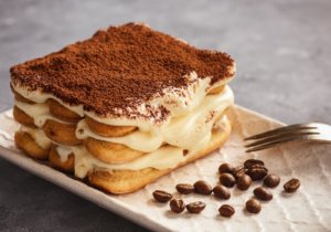 Tiramisu, uma das comidas típicas italianas mais famosas, com garfo ao lado e grão de café decorando