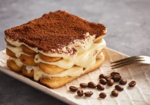 Tiramisu, uma das comidas típicas italianas mais famosas, com garfo ao lado e grão de café decorando