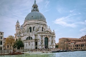 Canal, barcos e vista externa da basílica de santa maria della salute, um dos locais para visitar se você busca o que fazer em Veneza