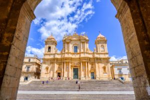 Catedral de noto, na Sicília, vista através de um arco, com céu azul emoldurando