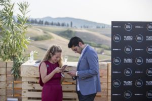 Um homem e uma mulher no coquetel VIP do show de Andrea Bocelli na Toscana, com paisagem ao fundo