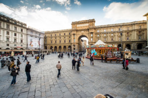 Panoramic view of Piazza della Repubblica in Florence, Italy, with people passing by, buildings and carousel