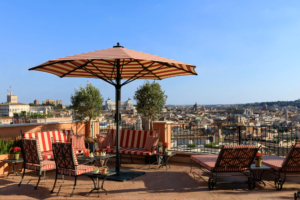 Terraço com cadeiras e guarda sol com vista para Roma no Hotel de la Ville, um dos hotéis de luxo em Roma