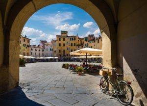 Bicycle and Piazza dell'Anfiteatro in Lucca, Tuscany, Italy, seen from one of the arches around the square