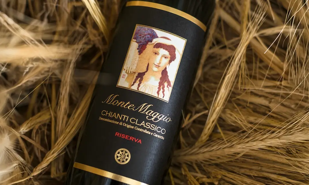Garrafa de vinho Monte Maggio Chianti Classico Riserva sobre palha seca, com rótulo artístico e design elegante